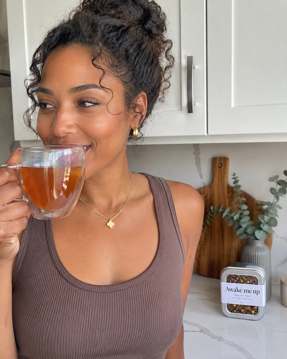 A woman enjoying a warm cup of Awake Me Up tea in her kitchen